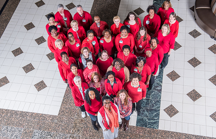 Employees wearing red and standing in the shape of a heart