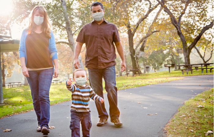 Mom, dad, and son walking on a path in a park on a sunny day