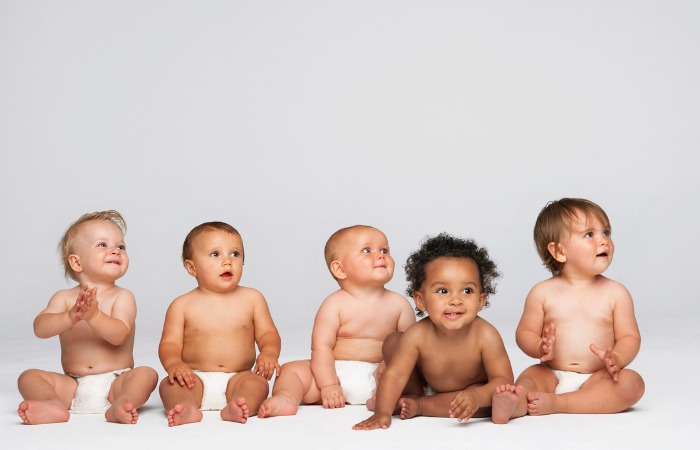 Five babies sitting in white diapers