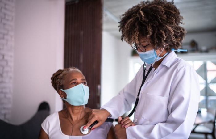 African American female doctor listening to patient's heart with a stethoscope