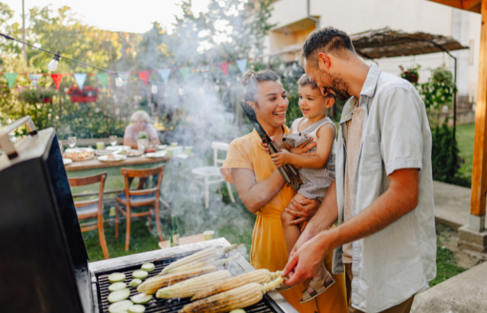 Father, mother, and son enjoy grilling together outside during the summer