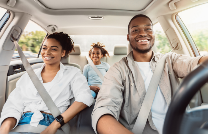 Family smiling and wearing seatbelts in car