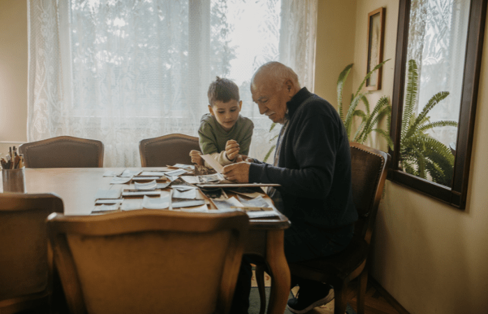 Grandfather looking at photos with his grandson in his living room