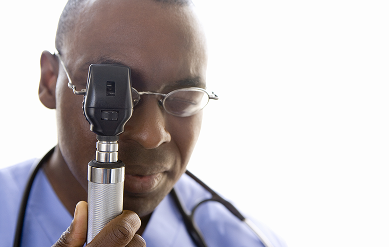 Male physician using an otoscope