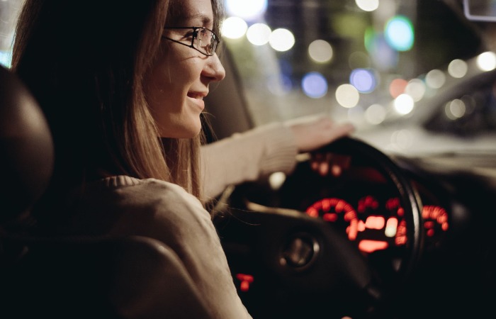 Young female wearing glasses, driving a car