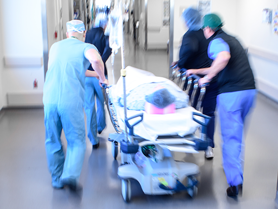 Nurses quickly rolling patient through hospital on a stretcher