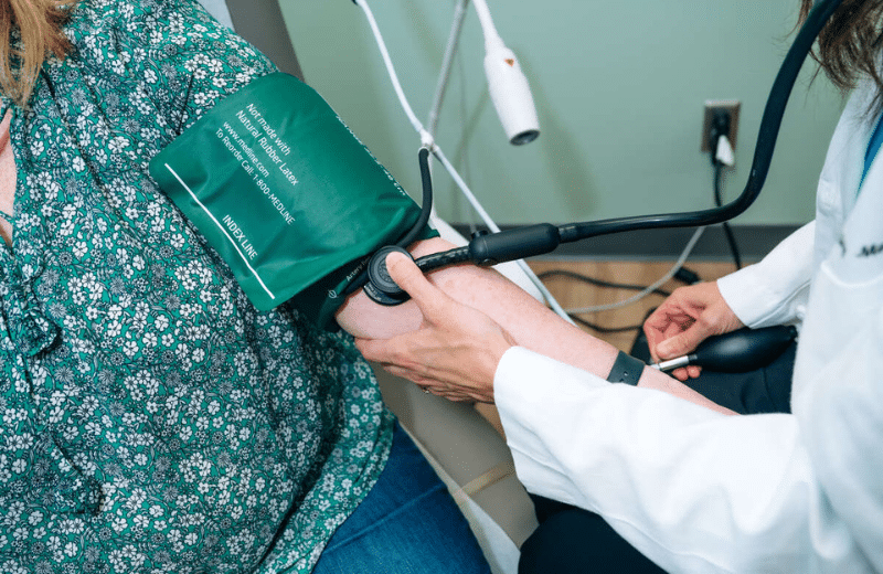 image shows a women having her blood pressure taken by a female doctor