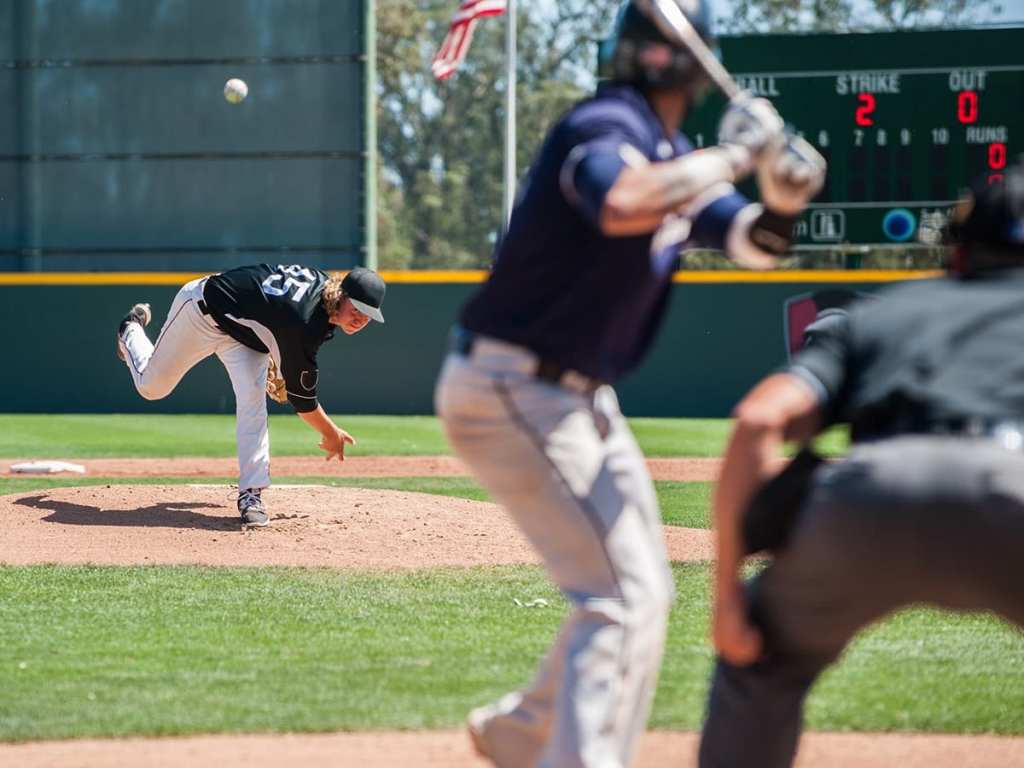 Mens' baseball pitcher throwing the curveball to the batter.