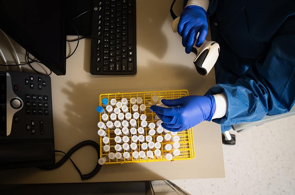 gloved employee scanning samples in the lab
