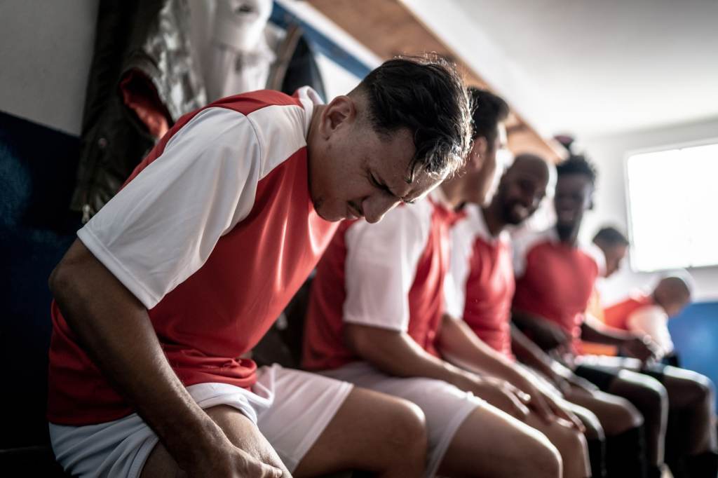 Injured soccer player pressing his thigh in the locker room