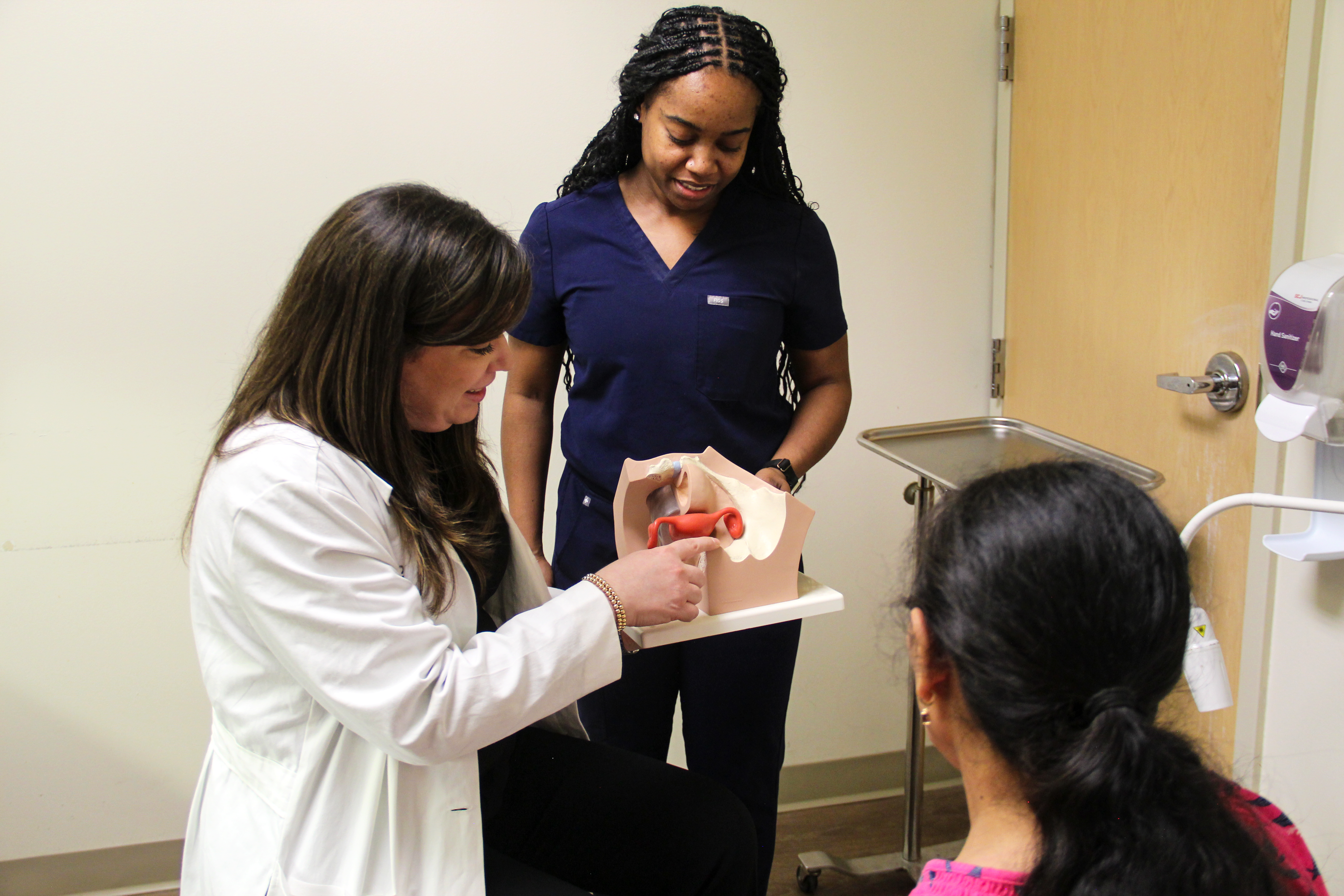 Gabriela Halder, MD, MPH explaining a 3d model of a uterus to a patient in front of a nurse.