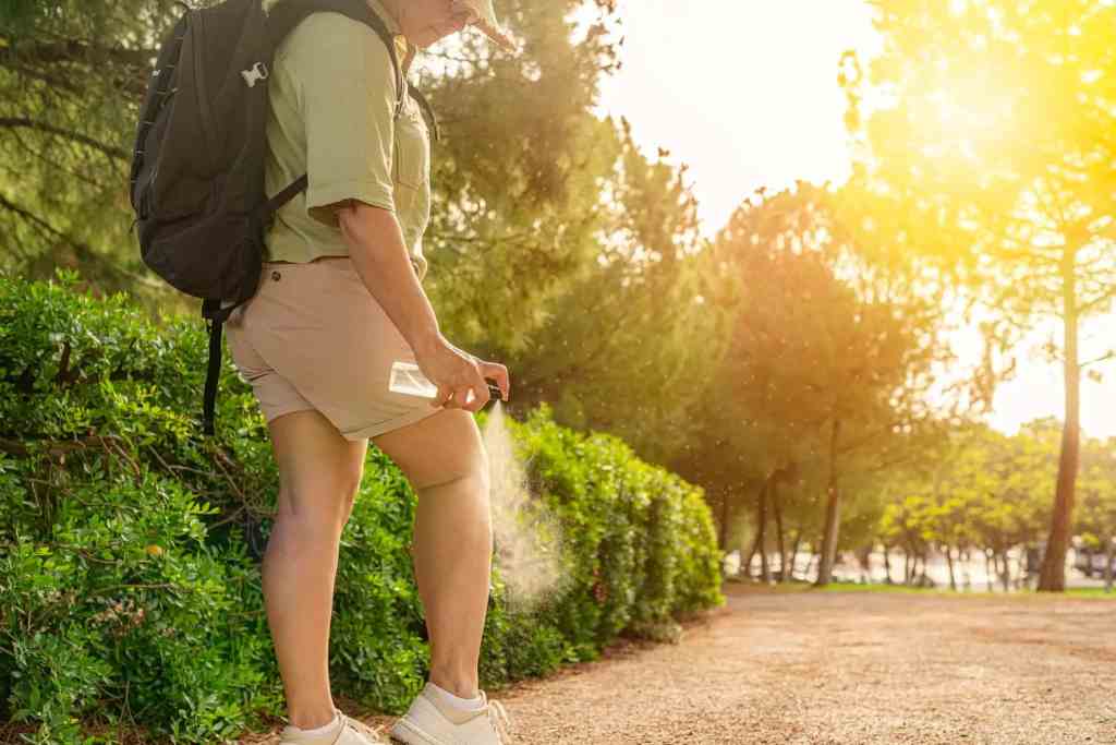 women spraying insect repellent on her leg