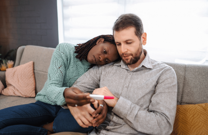 a couple looking disappointedly at a pregnancy test
