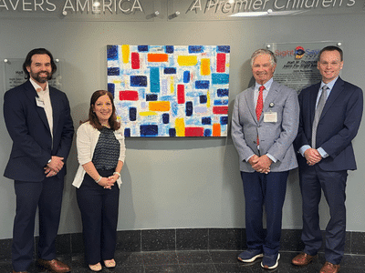 Logan Balandrin, Dianne Scalici, Michael Callahan, and Brian Samuels stand next to the 2026 Hall W. Thompson Hero for Sight tribute wall