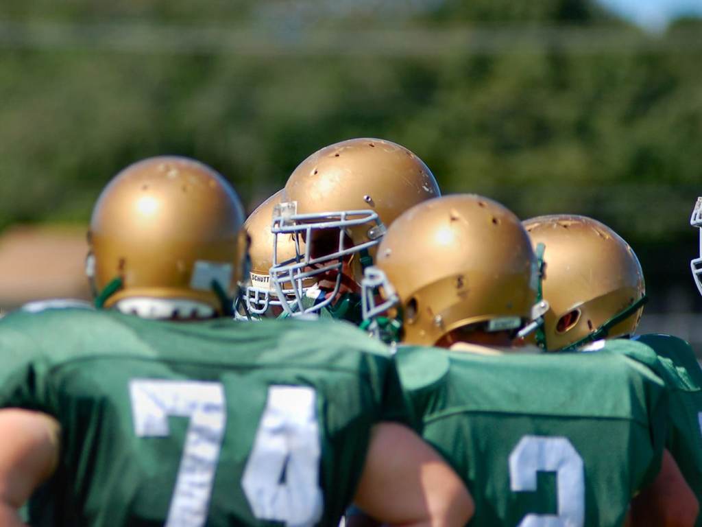 student athlete football players in a huddle